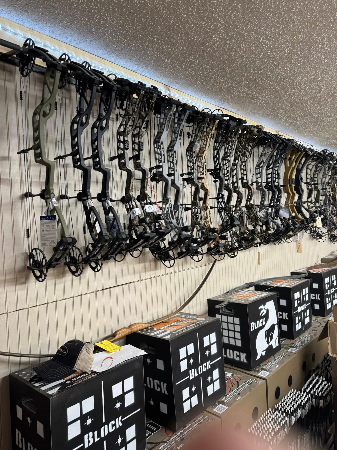 Wall of compound bows and archery targets inside the store